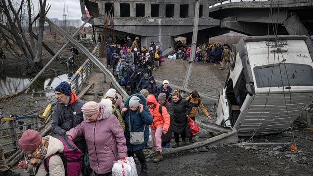 Menschen aus der Ukraine überqueren den Fluss Irpin auf einem improvisierten Weg unter einer zerstörten Brücke. Menschen aus der Ukraine überqueren den Fluss Irpin auf einem improvisierten Weg unter einer zerstörten Brücke.