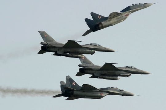 Zwei Mig 29 der polnischen Luftwaffe aus russischer Produktion fliegen über und unter zwei F-16-Kampfjets der polnischen Luftwaffe aus amerikanischer Produktion.