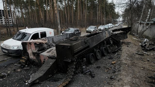 Autos fahren an einem zerstörten russischen Panzer in der Nähe von Irpin am Stadtrand von Kiew vorbei. Autos fahren an einem zerstörten russischen Panzer in der Nähe von Irpin am Stadtrand von Kiew vorbei.