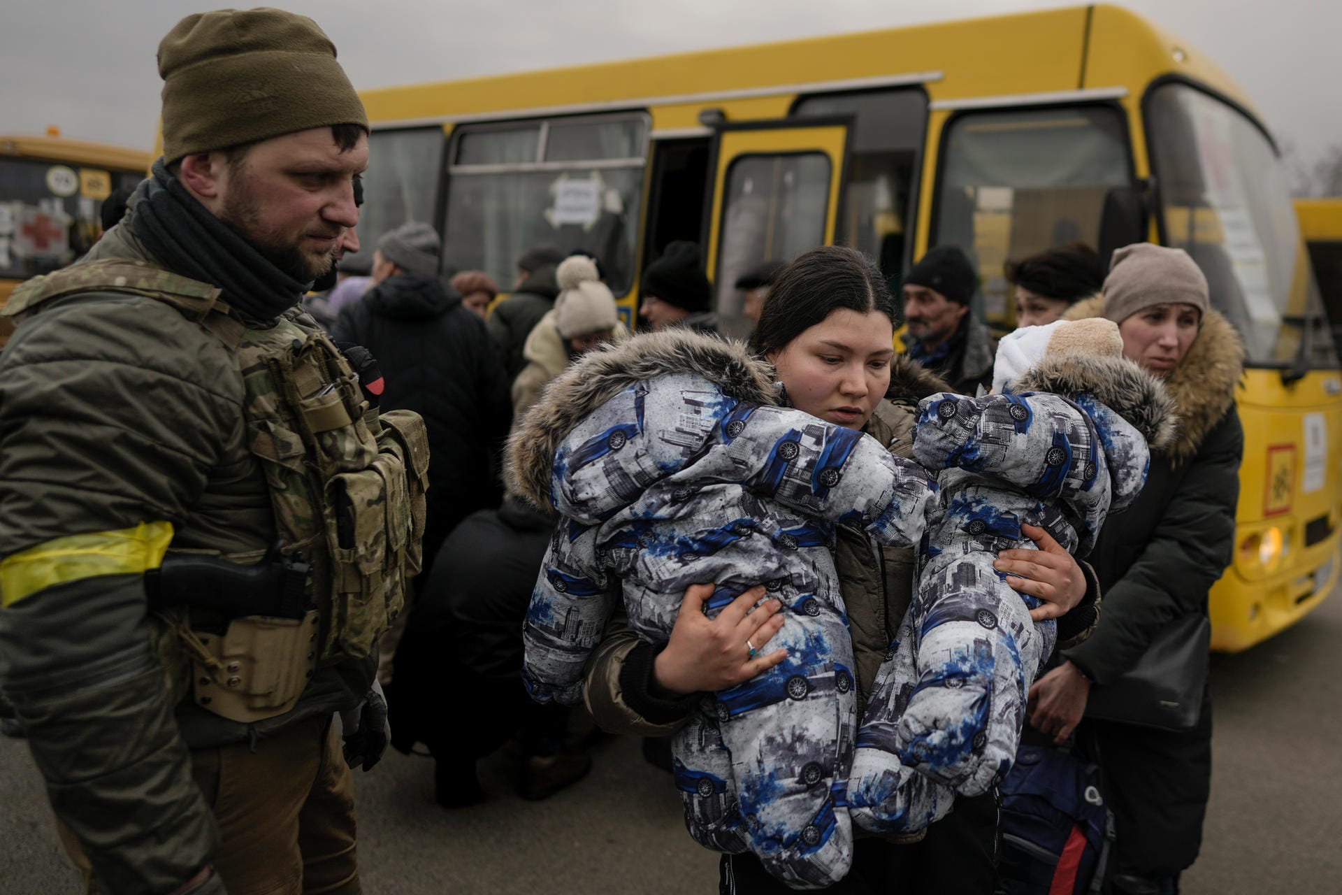 Eine Frau trägt zwei Kinder während der Evakuierung: Die Belastungen für die Familien sind enorm, die Fluchtwege unsicher.