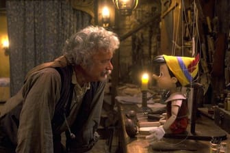 Tom Hanks (l) als Holzschnitzer Geppetto beugt sich zum computeranimierten Pinocchio herunter.