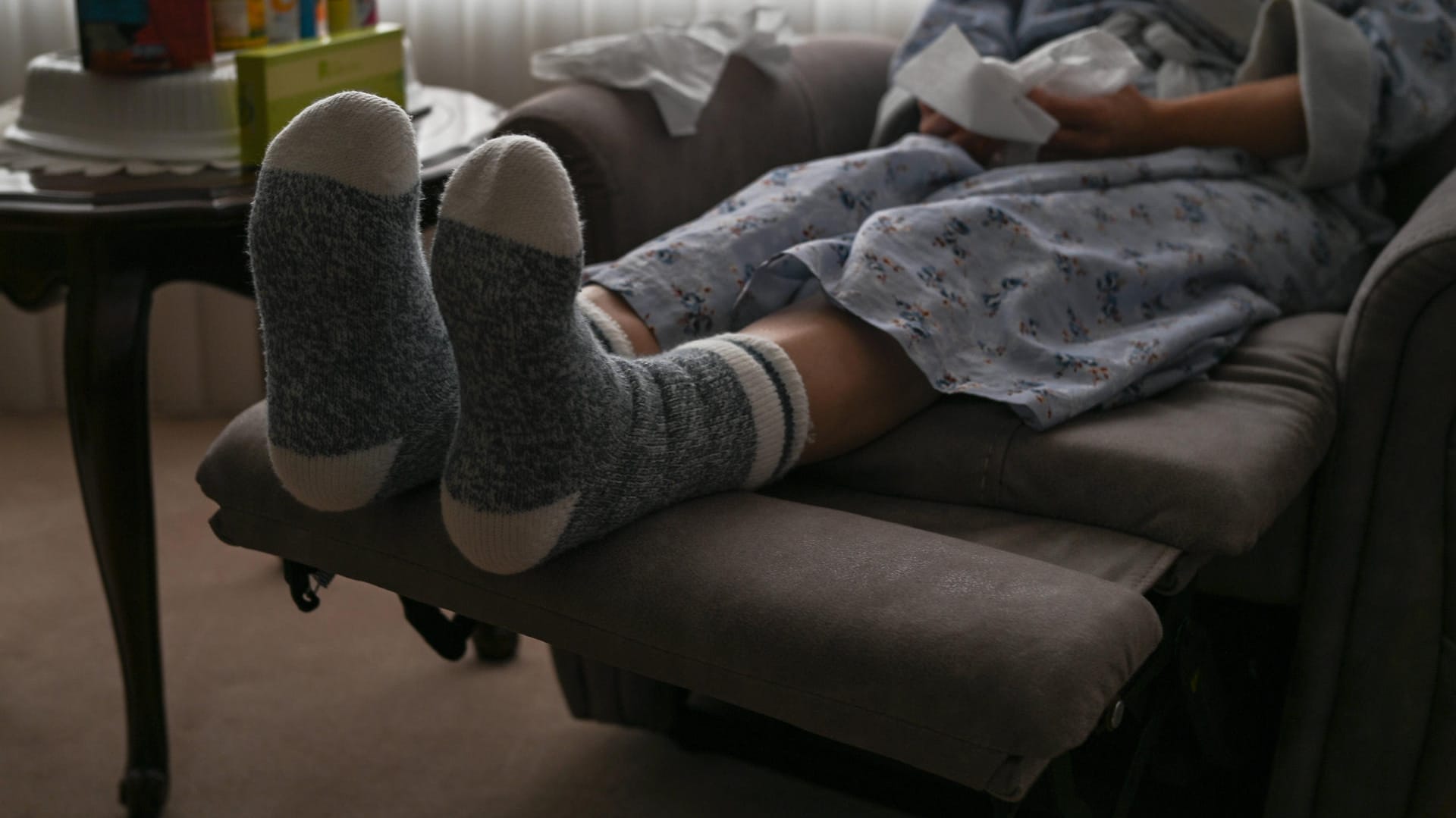 Eine Frau sitzt mit dicken Socken im Wohnzimmer (Symbolbild): Auch Ex-Bundespräsident Joachim Gauck schlägt vor, für die Freiheit zu frieren. Doch abdrehen muss man seine Heizung zum Energiesparen wirklich nicht.