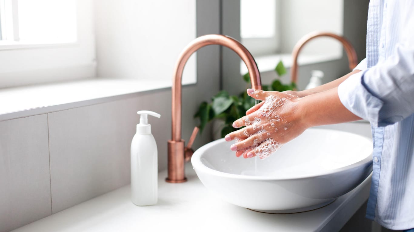 Eine Frau wäscht sich die Hände mit Seife.