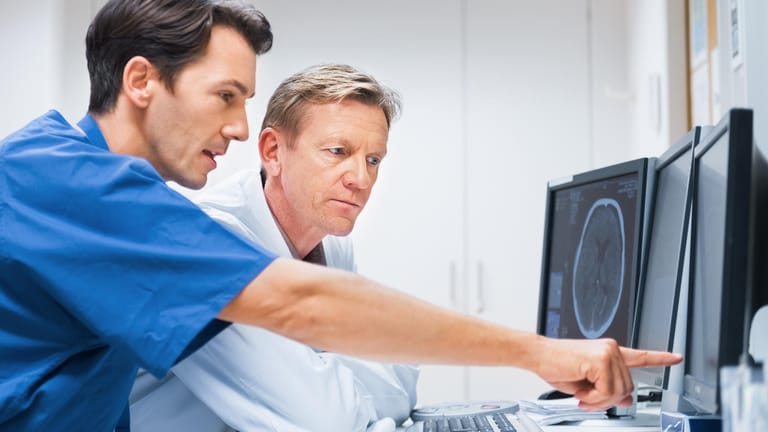 Zwei Ärzte betrachten eine Gehirnaufnahme am Monitor.