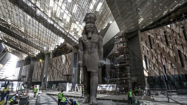 Arbeiter reinigen den Bereich neben der riesigen Statue des ägyptischen Pharaos Ramses II. Arbeiter reinigen den Bereich neben der riesigen Statue des ägyptischen Pharaos Ramses II.