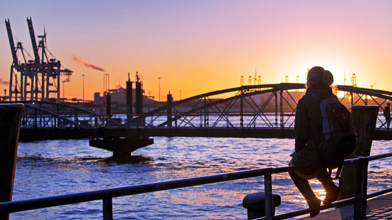Eine Frau sitzt bei Sonnenuntergang an der Norderelbe am Hamburger Hafen (Archivbild): Im Norden wird ein sonniges und windiges Wochenende erwartet.