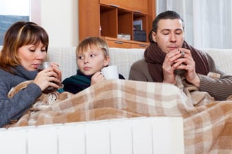 Eine Familie bevorzugt warme Kleidung, eine Decke und Heißgetränke: Die gestiegenen Heiz- und anderen Energiekosten machen erfinderisch.