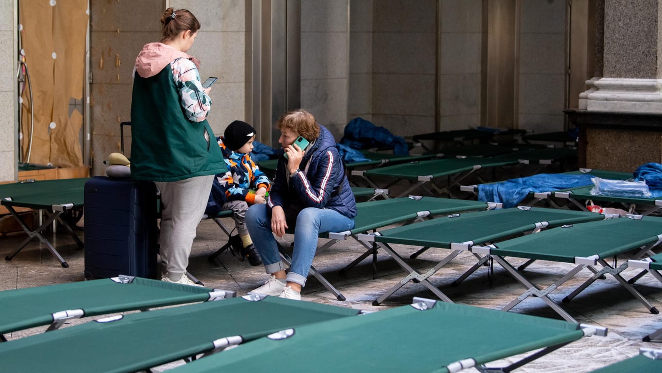 Flüchtlinge aus der Ukraine sitzen in einem Bettenlager am Münchner Hauptbahnhof. Für die vielen Menschen aus der Ukraine hat die Stadt teils zu wenig Plätze organisiert.