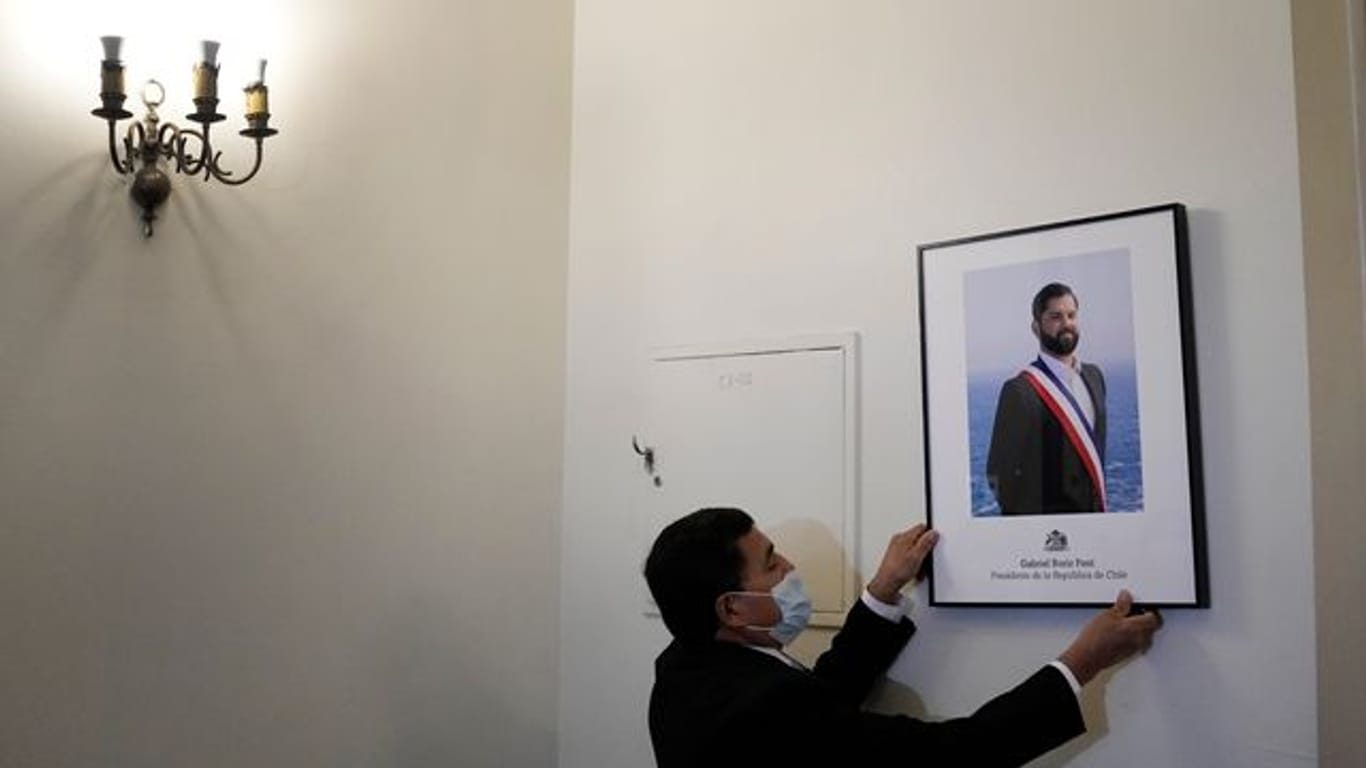 Ein Palastangestellter hängt das offizielle Porträt des neuen chilenischen Präsidenten Boric im Büro des Präsidentenpalastes La Moneda auf.