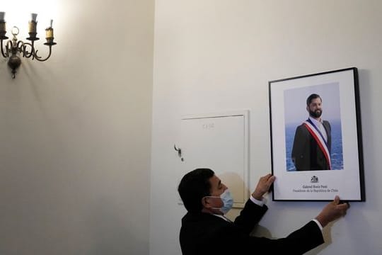 Ein Palastangestellter hängt das offizielle Porträt des neuen chilenischen Präsidenten Boric im Büro des Präsidentenpalastes La Moneda auf.