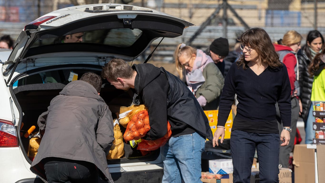 Freiwillige entladen das Auto von Barbara Demmer (rechts): Sie bringt Säcke voller Kartoffeln und Zwiebeln zur Sammelstelle.