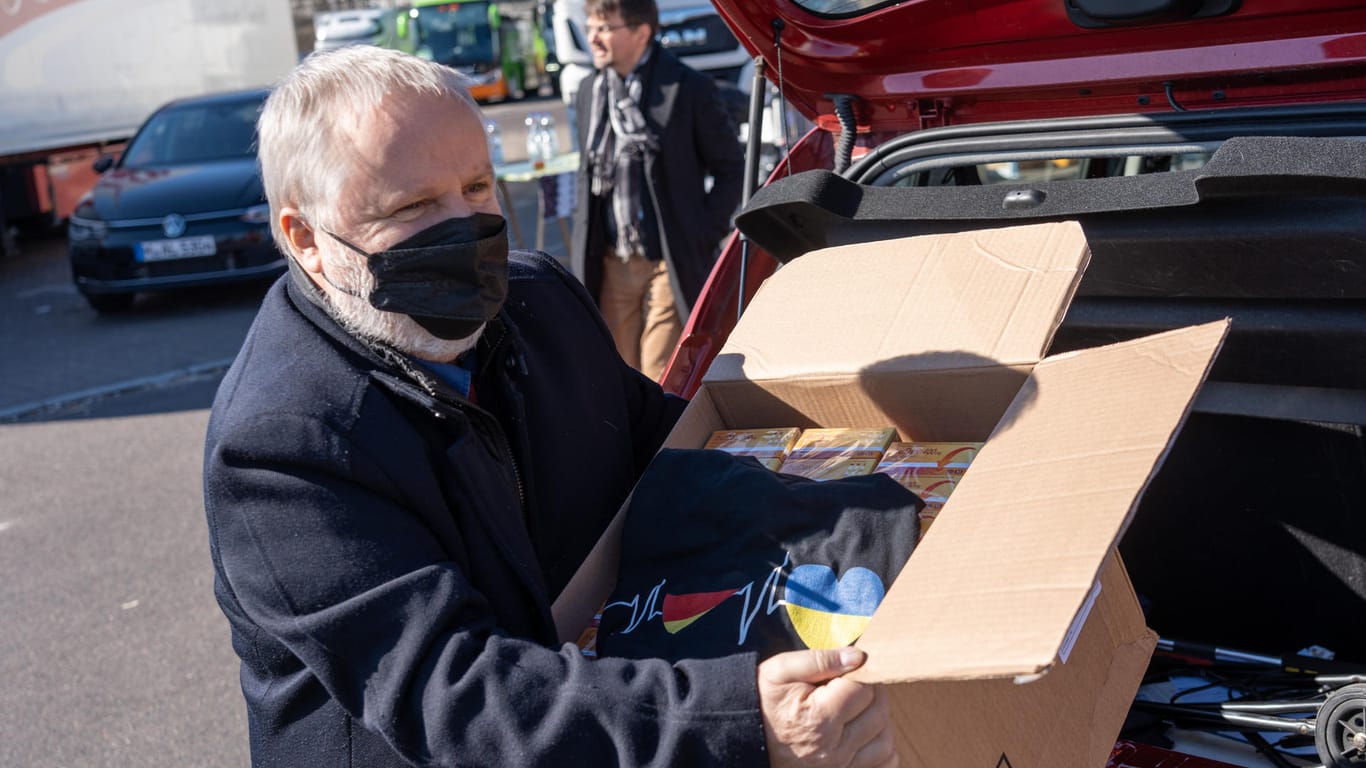 Claus Bredel-Charron lädt eine Kiste mit Medikamenten und einem bedruckten T-Shirt aus seinem Auto: Für die dringend benötigten Waren legte er mit seinem Sohn und einem Partner zusammen.