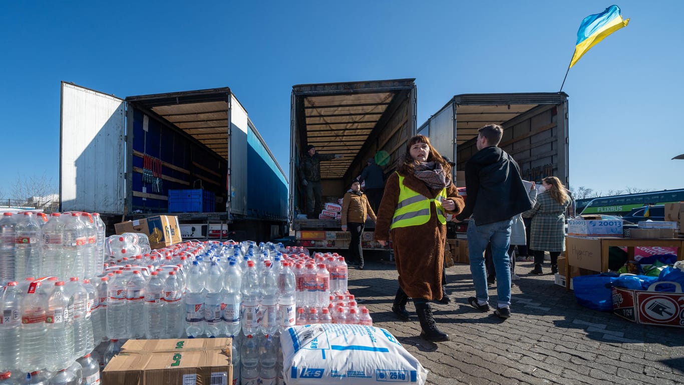 Palettenweise Wasserflaschen und andere gespendete Güter werden von Helfern in drei bereitstehende Lkw geladen: Auf dem Parkplatz herrscht hektische Betriebsamkeit.
