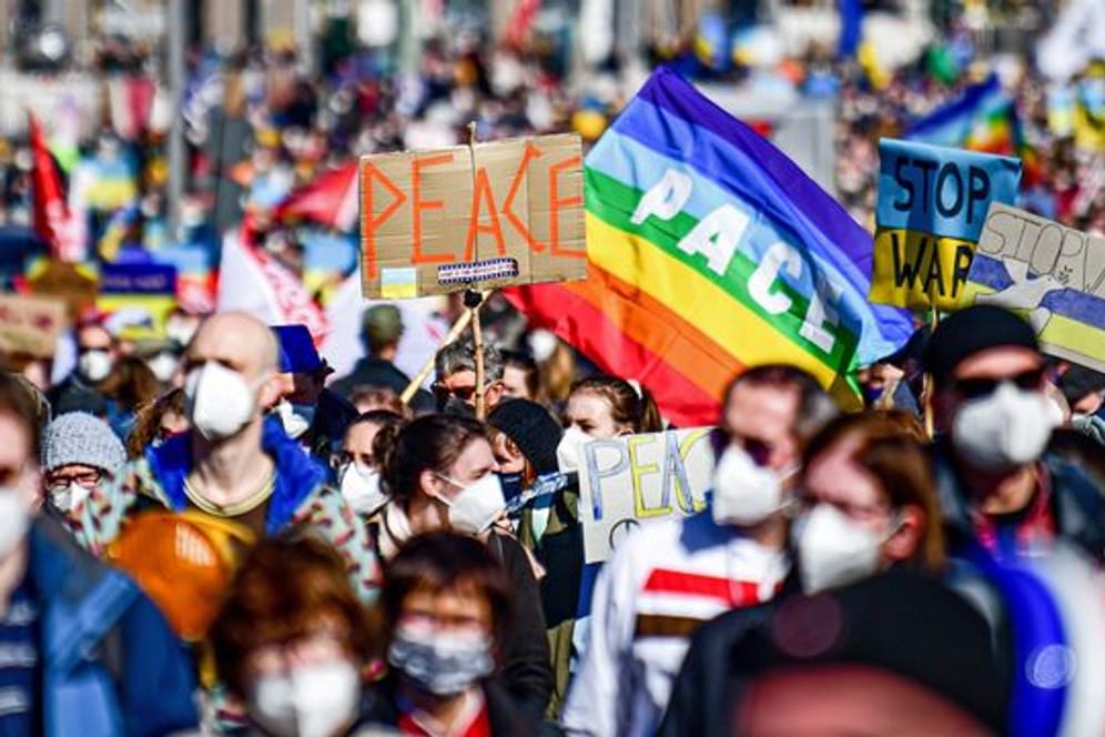 Menschen halten "Peace"-Schilder hoch, während sie an einer Friedensdemonstration gegen den Krieg in der Ukraine protestieren.