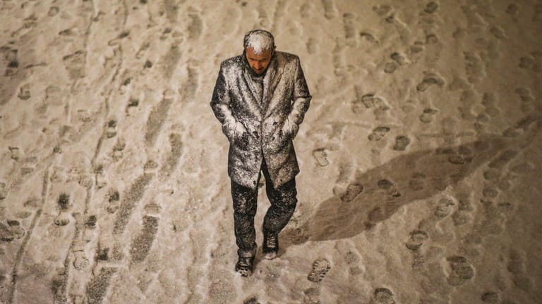 Ein Mann, der teilweise vom Schnee bedeckt ist, geht in Istanbul spazieren: In der Türkei herrscht derzeit extremes Winterwetter.