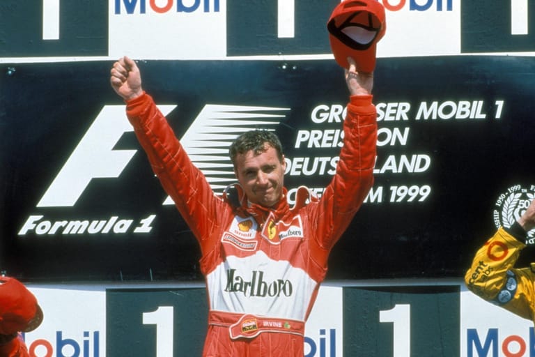 Eddie Irvine im Ferrari-Overall beim Großen Preis von Deutschland 1999 – die Saison war die erfolgreichste für den Nordiren, mit nur zwei Punkten Rückstand auf Mercedes-Pilot Mika Häkkinen wurde er Vizeweltmeister. Von 1993 bis 2002 fuhr Irvine in der Formel 1, davon vier Jahre gemeinsam mit Michael Schumacher bei der "Scuderia" (1996-99).