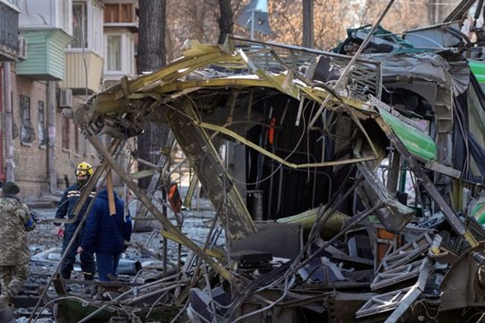 Soldaten stehen nach einem Bombenangriff auf einer Straße in Kiew neben einer zerstörten Straßenbahn.