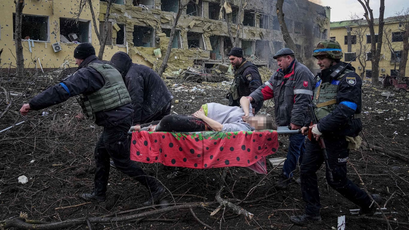 Ukrainische Rettungskräfte und Freiwillige tragen eine verletzte schwangere Frau aus einer Entbindungsklinik in Mariupol: Die Frau wurde bei dem Beschuss der Klinik tödlich verletzt.