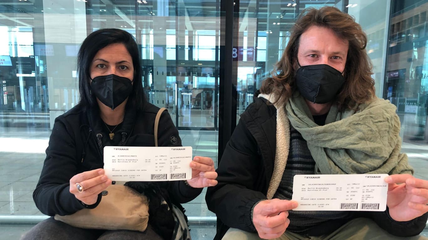 Marta und Ruben halten am BER ihre Flugtickets in der Hand: Sie sitzen bereits seit 8 Uhr morgens am Flughafen.