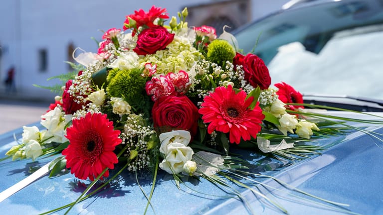 Blumen auf der Motorhaube eines Autos (Symbolbild): Gegen Teilnehmende des Autokorsos wird nun ermittelt.