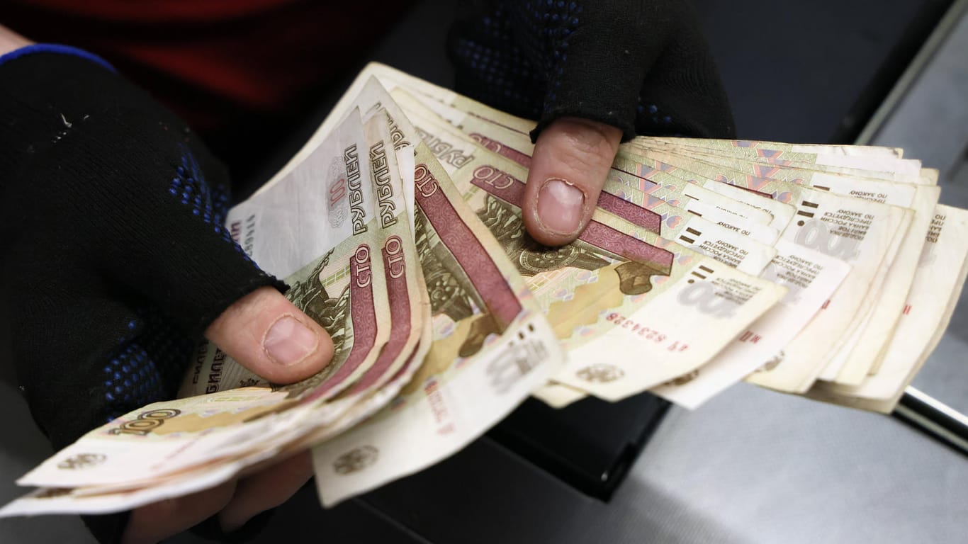 Ein Kassierer hält Rubel-Scheine in der Hand: Die russische Währung verlor wegen Putins Krieg drastisch an Wert.