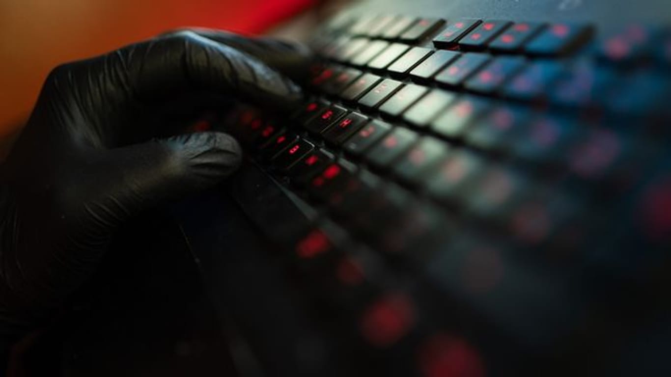 Ein Mann trägt Handschuhe und tippt auf der Tastatur eines Computers (Symbolbild): Ermittler haben zwei Bremer Verdächtige im Visier.