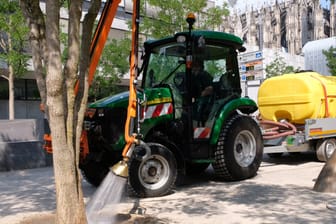 Ein Schlepper der Stadt Köln bewässert Bäume am Straßenrand aus einem Wassertank: Mittlerweile sind vier solcher Fahrzeuge im Stadtgebiet unterwegs.