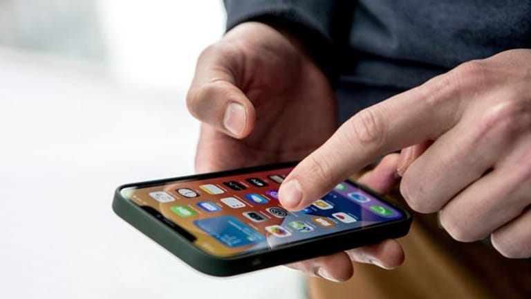 Ein Mann tippt auf den Bildschirm von einem iPhone 12.