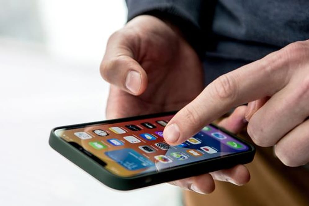 Ein Mann tippt auf den Bildschirm von einem iPhone 12.