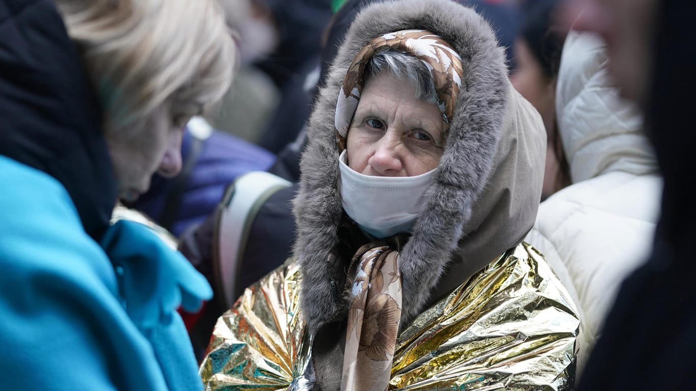 Eine ältere Frau schützt sich mit einer Erste-Hilfe-Decke in der Warteschlange an der Hammer Straße vor der Kälte.