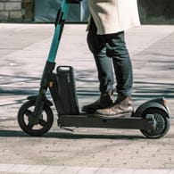 Eine Person fährt mit einem E-Scooter auf dem Gehweg (Symbolbild): Warum es zu der Kollision kam, ist Gegenstand der Ermittlungen.