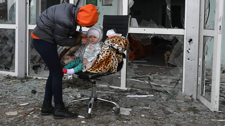 Frau und Kind vor dem zerstörten Krankenhaus von Wolnowacha in der Ostukraine: Auch in Lwiw kommt es zu erheblichen Engpässen.