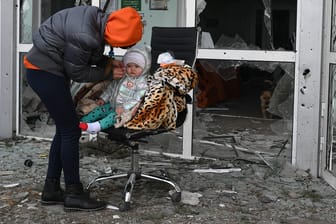 Frau und Kind vor dem zerstörten Krankenhaus von Wolnowacha in der Ostukraine: Auch in Lwiw kommt es zu erheblichen Engpässen.