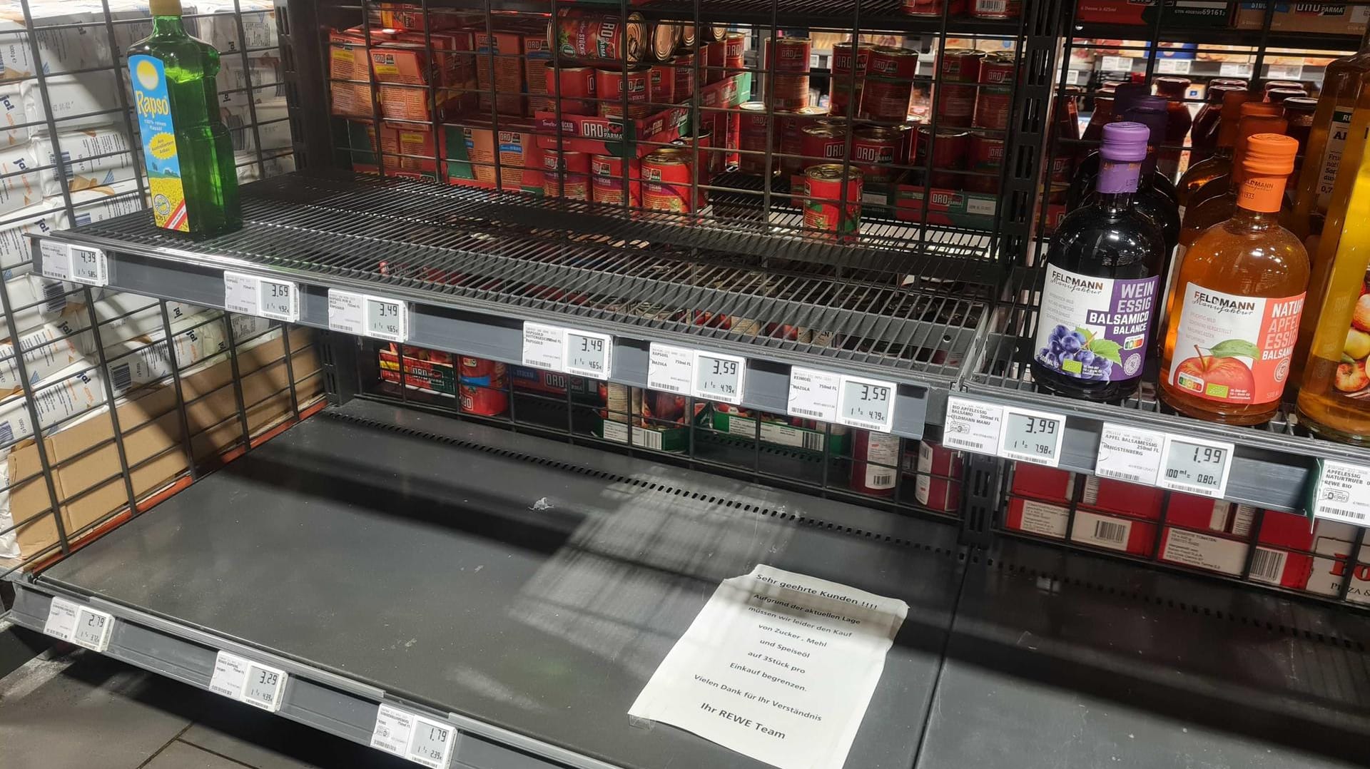 Ausverkauftes Regal in einem Kölner Supermarkt: Ein Schild weist Kunden auf die Mitnahmebegrenzung für Speiseöl, Zucker und Mehl hin.