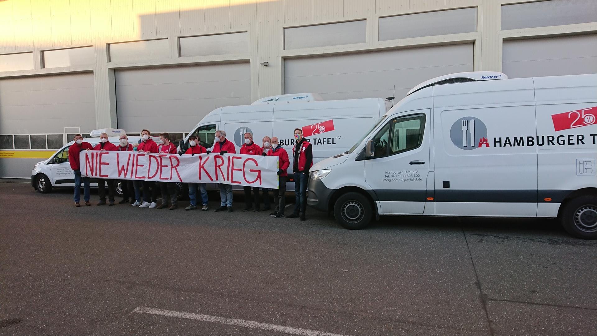 Mitarbeitenden der Hamburger Tafel halten ein Protestbanner gegen den Krieg in der Ukraine hoch. Etwa 20.000 Kilometer legt die Flotte der Tafel im Monat zurück.