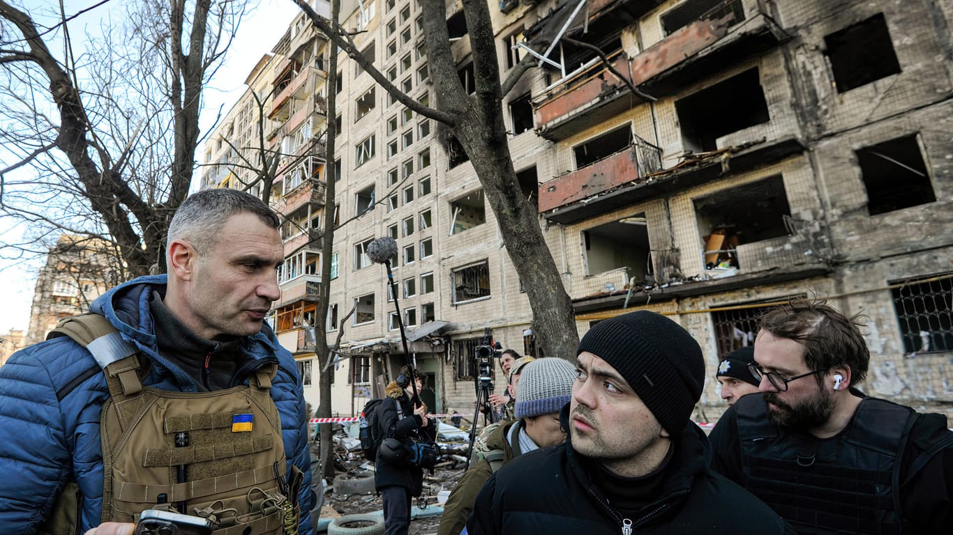 Der Bürgermeister von Kiew und ehemalige Profiboxer Vitali Klitschko (l.) spricht zu Anwohnern in der Nähe eines Wohnhauses, das von der russischen Armee beschossen wurde.