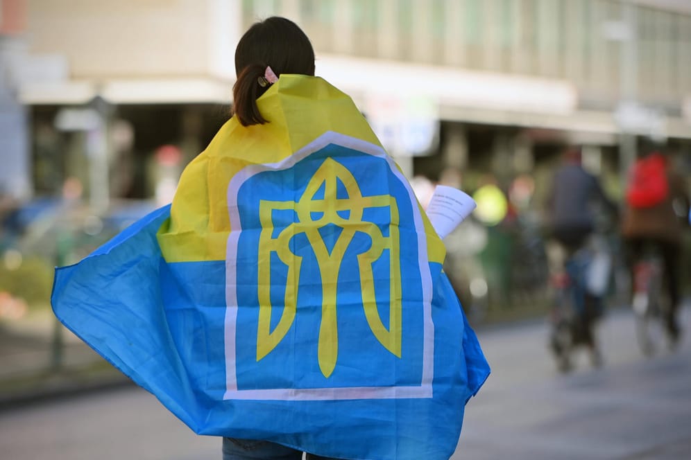 Eine Frau mit einer ukrainischen Flagge in München (Symbolbild): Viele Menschen aus der Ukraine flüchten derzeit vor dem Krieg, auch nach München.