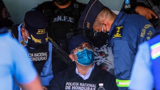 Juan Orlando Hernandez (M), Ex-Präsident von Honduras, spricht mit Polizeibeamten nach seiner Festnahme in seinem Haus.