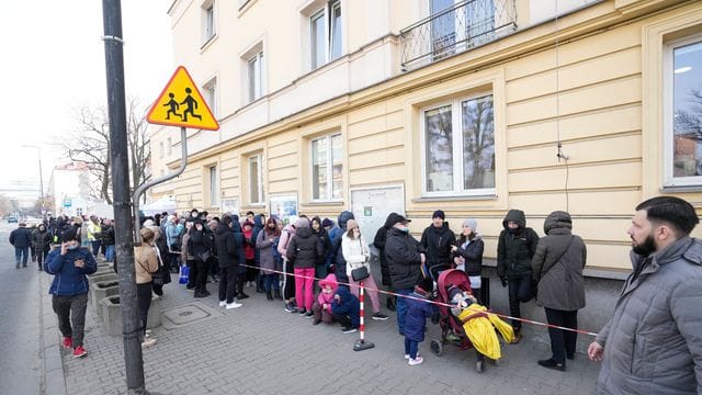 Aus der Ukraine geflüchtete Menschen stehen vor einer Meldestelle Schlange.