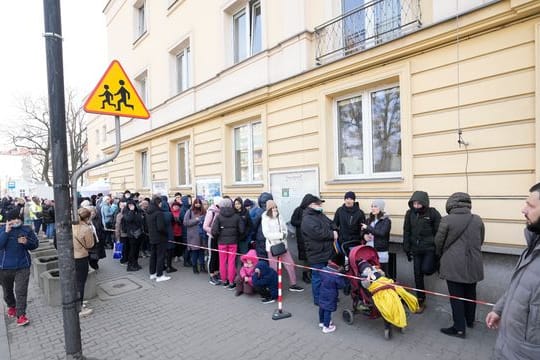 Aus der Ukraine geflüchtete Menschen stehen vor einer Meldestelle Schlange.