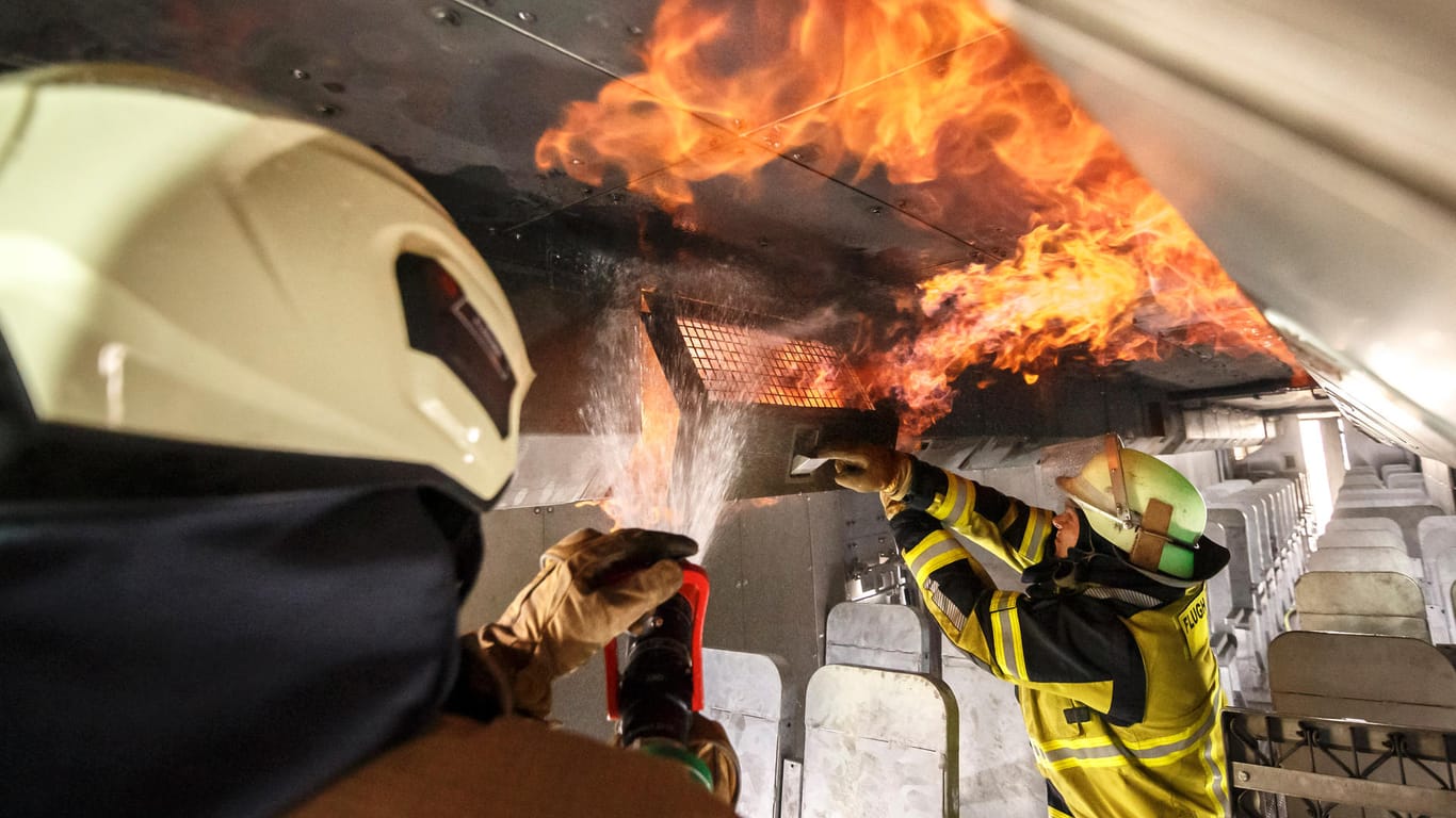Feuerwehrleute löschen einen simulierten Brand in einem Gepäckfach: Jedes Jahr müssen die die Flughafenwehren die Übungen absolvieren.