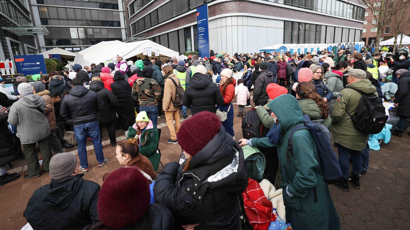 Menschen, die aus der Ukraine geflohen sind, warten vor dem Amt für Migration in Hamburg und werden von freiwilligen Helfern mit Essen, Getränken und verschiedenen Dingen des täglichen Gebrauchs versorgt.