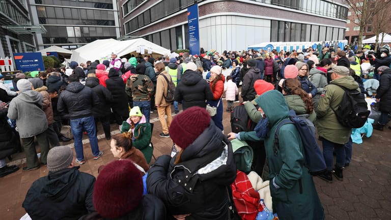 Menschen, die aus der Ukraine geflohen sind, warten vor dem Amt für Migration in Hamburg und werden von freiwilligen Helfern mit Essen, Getränken und verschiedenen Dingen des täglichen Gebrauchs versorgt.
