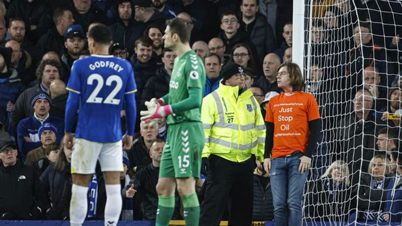 Ein Demonstrant (r) hat sich beim FC Everton mit einem Kabelbinder an den Torpfosten gebunden.