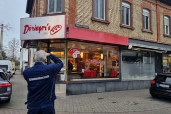 Ein Kriminaltechniker fotografiert die Bäckerei: Mit einer Holzlatte haben zwei unbekannte Täter in Mannheim eine Bäckerei gestürmt.