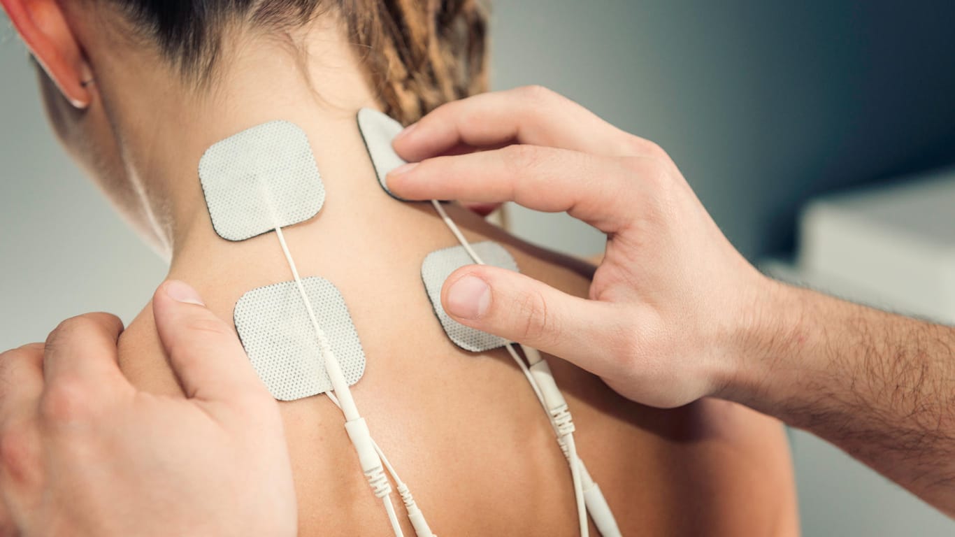TENS-Elektroden im Nacken-Schulter-Bereich bei einer Frau.