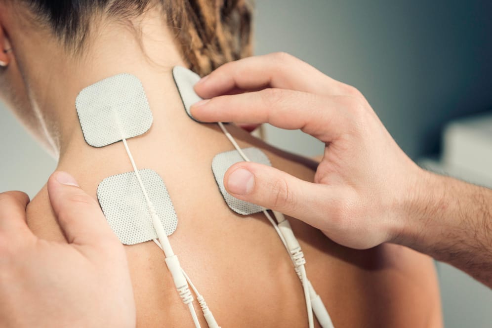 TENS-Elektroden im Nacken-Schulter-Bereich bei einer Frau.