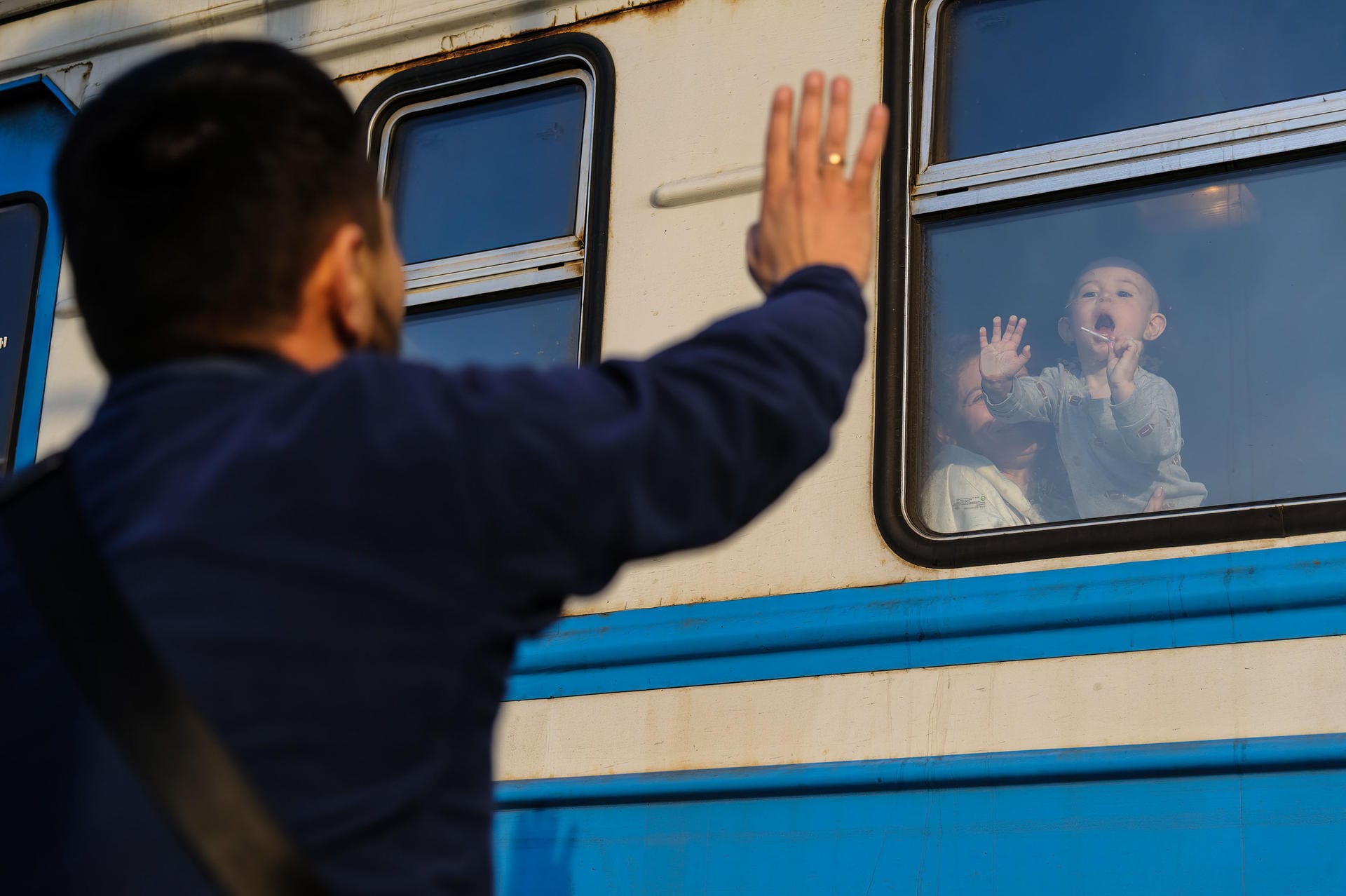 Ein Mann gestikuliert vor einem Zug nach Polen am Bahnhof von Lwiw zu seinem Kind: Die Stadt ist zu einem Transitknotenpunkt für Frauen und Kinder geworden, die nach Polen fliehen, während die wehrpflichtigen Männer zurückbleiben, um das Land zu verteidigen.