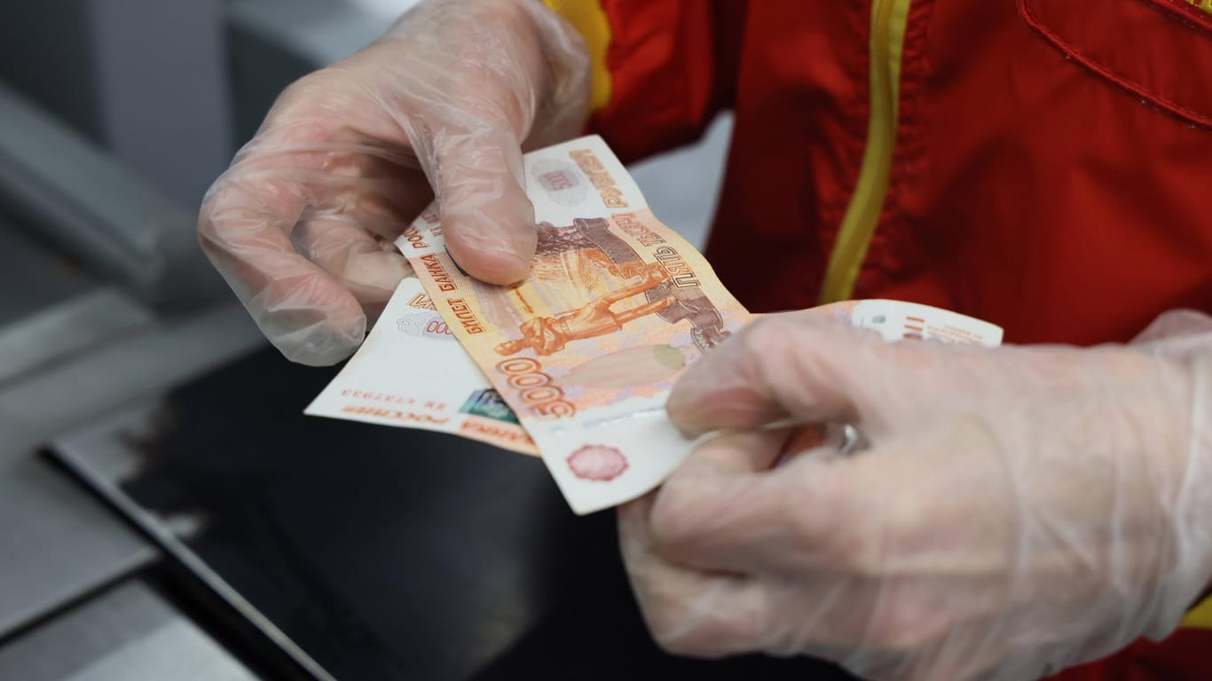 Kassierer hält Rubel-Banknote in der Hand (Symbolbild): Die russische Währung verlor in den vergangenen Wochen drastisch an Wert.