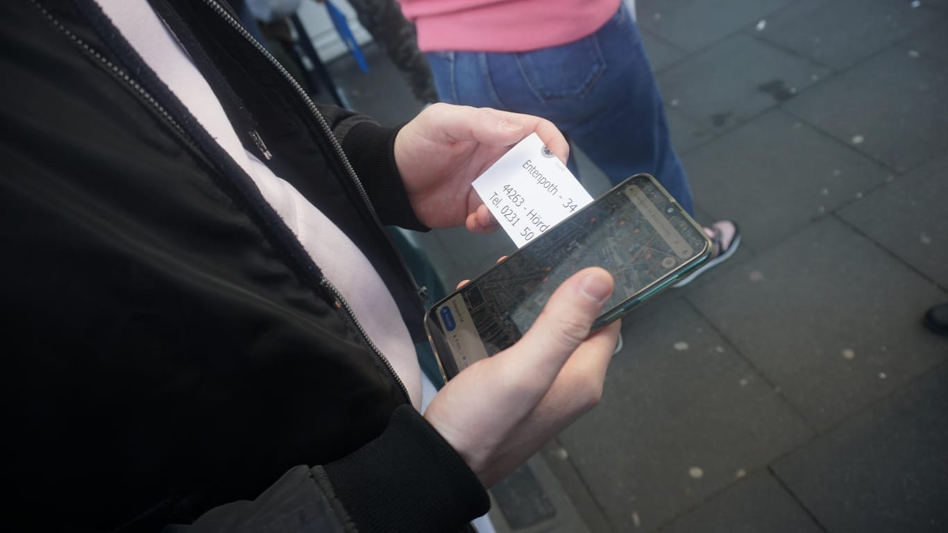 Ein Mann hält ein Handy in der Hand: Es zeigt die Route zu einem zweiten Standort des Sozialamtes in Dortmund.